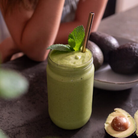 Vibrant, green creamy avocado smoothie, surrounded by avocados