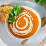 Vibrant bowl of roasted tomato soup with sourdough for dipping