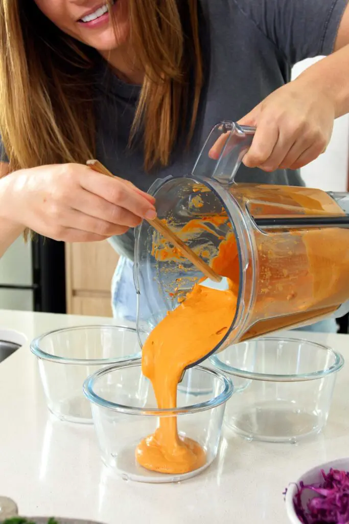 Adding the Romesco sauce to the bottom of the meal prep containers