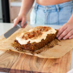 A freshly baked plant-based Pumpkin Spice Baked Oats with protein icing on baking paper, ready to be sliced