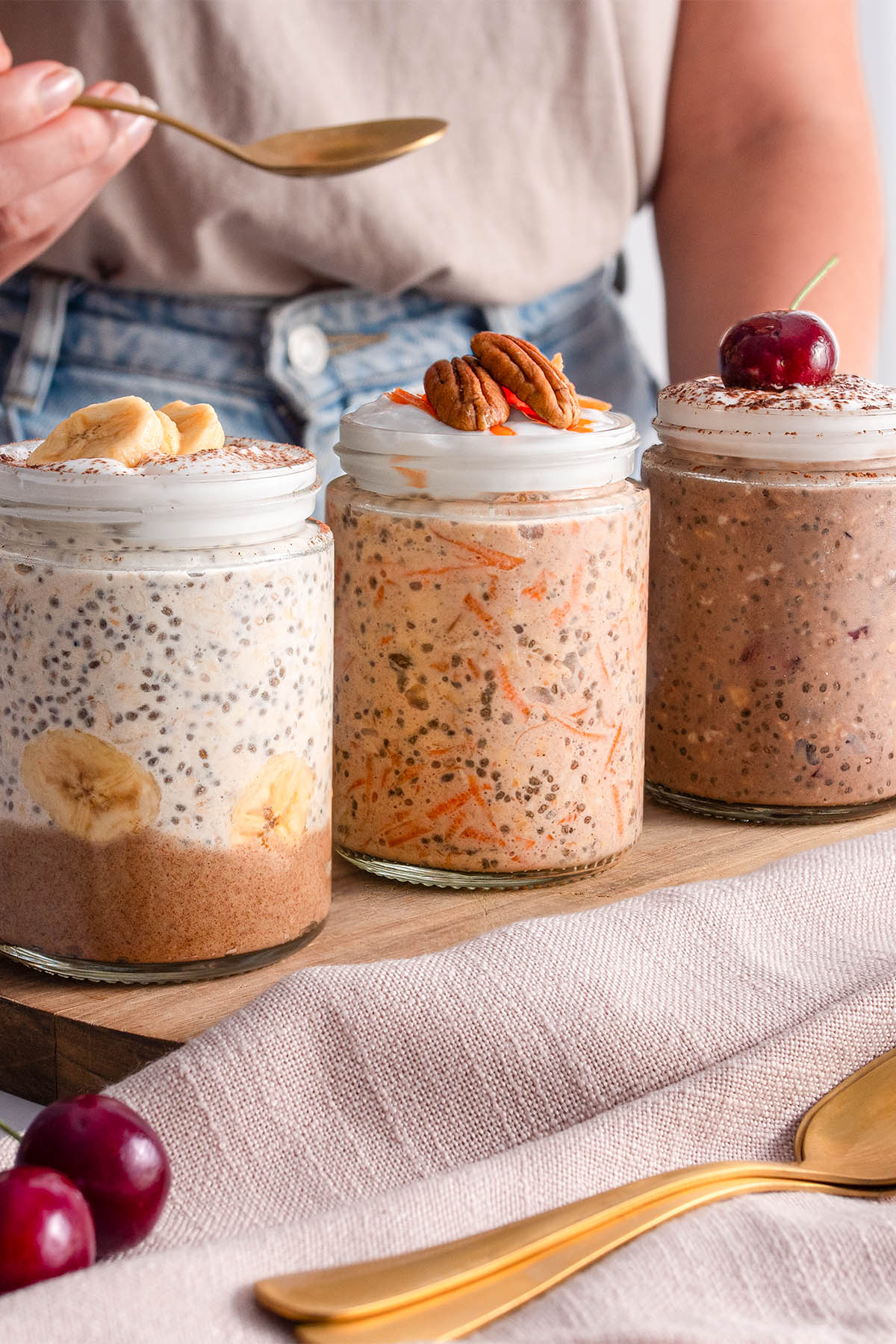 Three varying jars of overnight oats with golden spoons