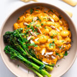 Serving of High-Protein Romesco Butter Beans with garnished parsley and side of broccolini on a clean white background.