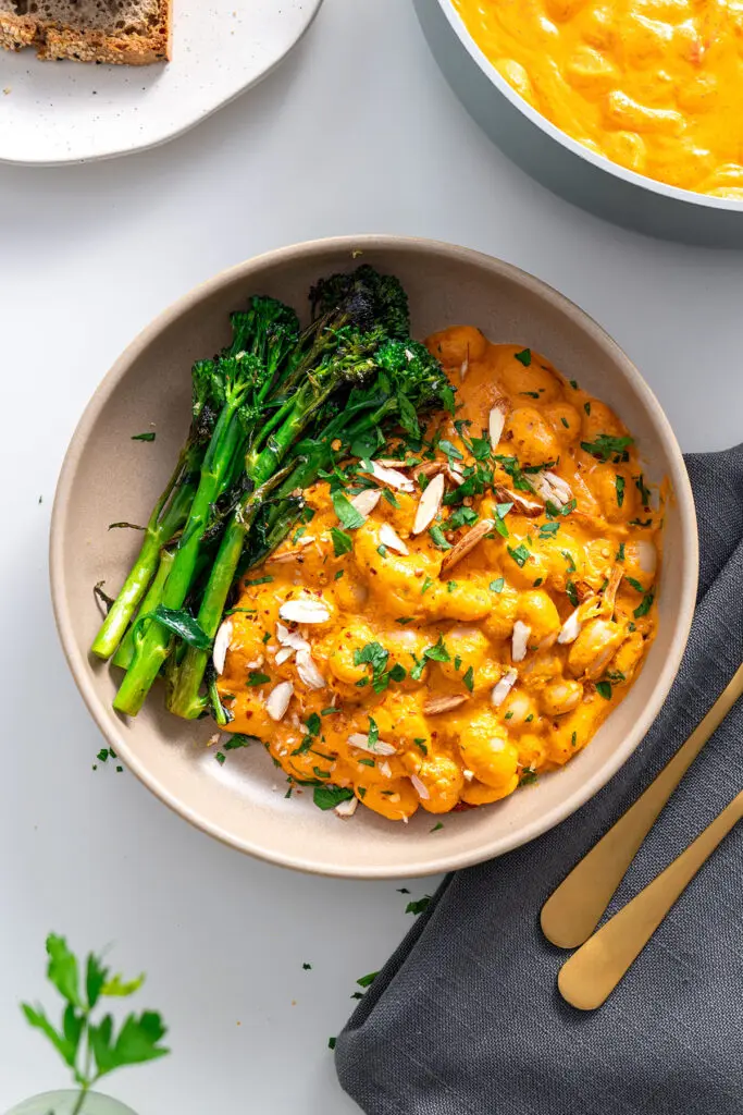 Top-down view of a bowl of High-Protein Romesco Butter Beans with chopped almonds and parsley