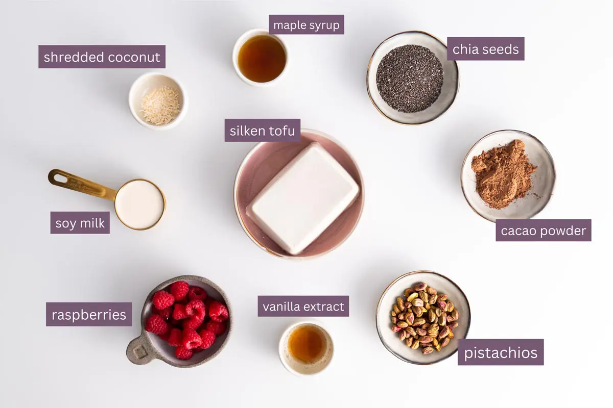 Top view of vibrant ingredients for Chocolate Pistachio Chia Pudding on a white surface.