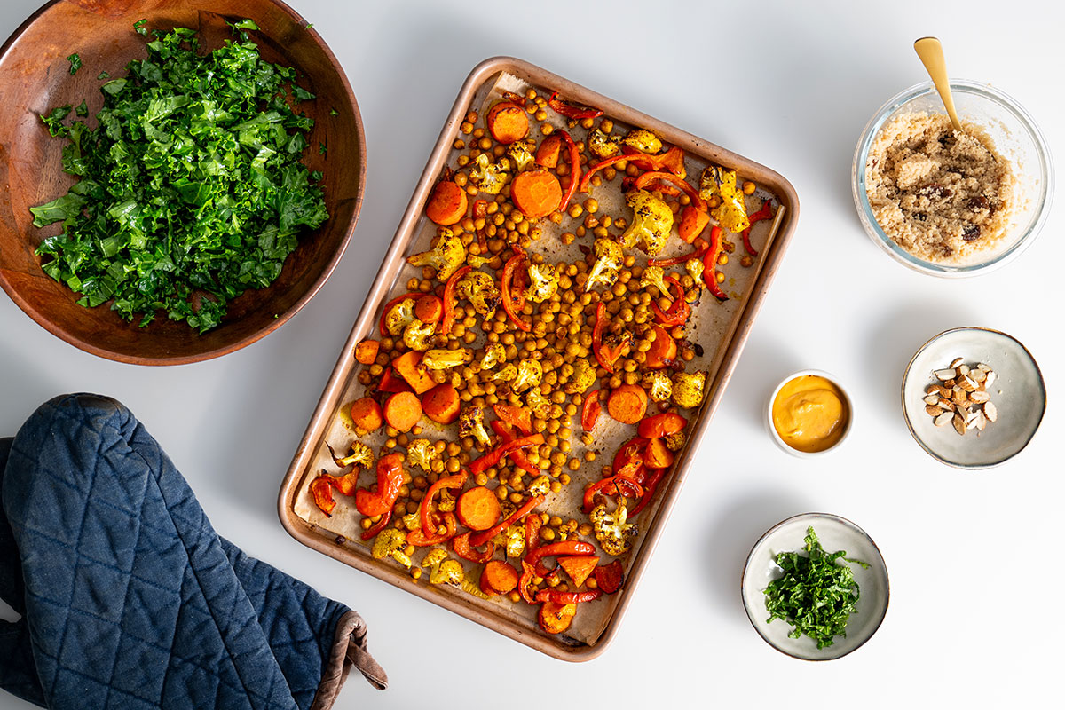 Oven tray with roasted vegetables and chickpeas for a Moroccan-inspired nourish bowl.