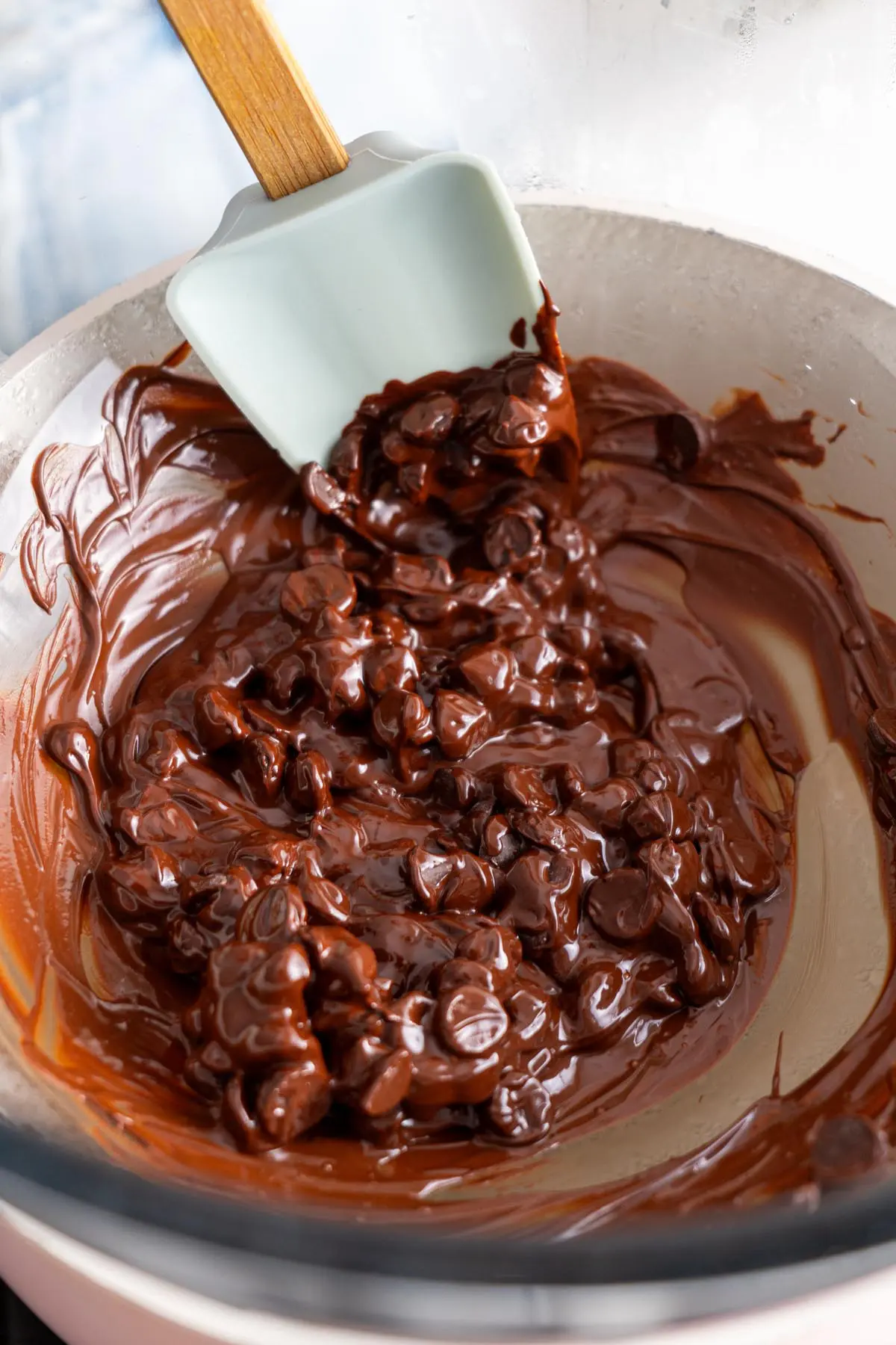 Dark chocolate chips melting in a bowl over a pot of simmering water.
