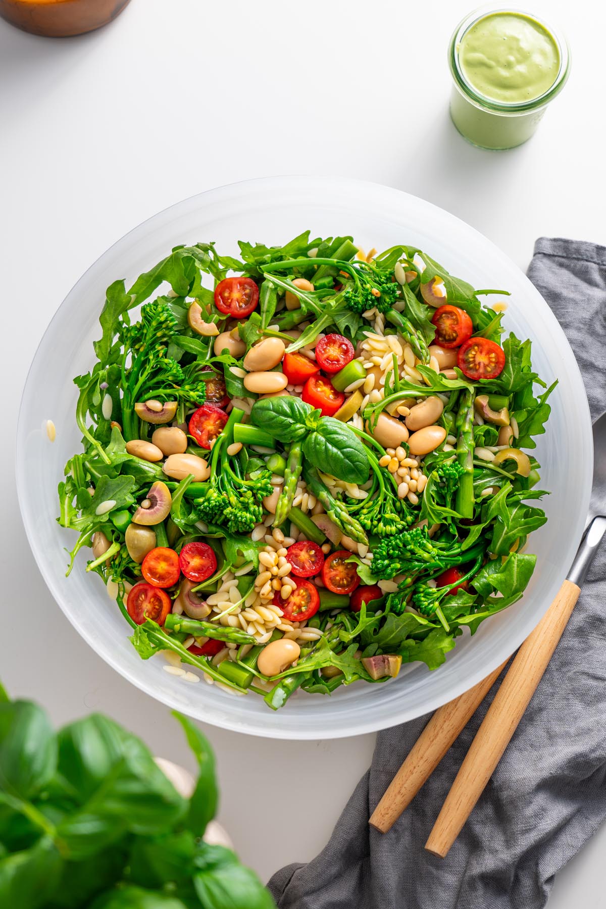 Nhìn từ trên xuống của Salad Pesto Orzo mới chế biến trong một chiếc bát màu trắng trên quầy bếp, có rau arugula, bông cải xanh và cà chua bi.