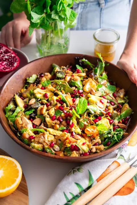 Close-up of spiced roasted cauliflower and chickpea salad in a wooden bowl with fresh ingredients.