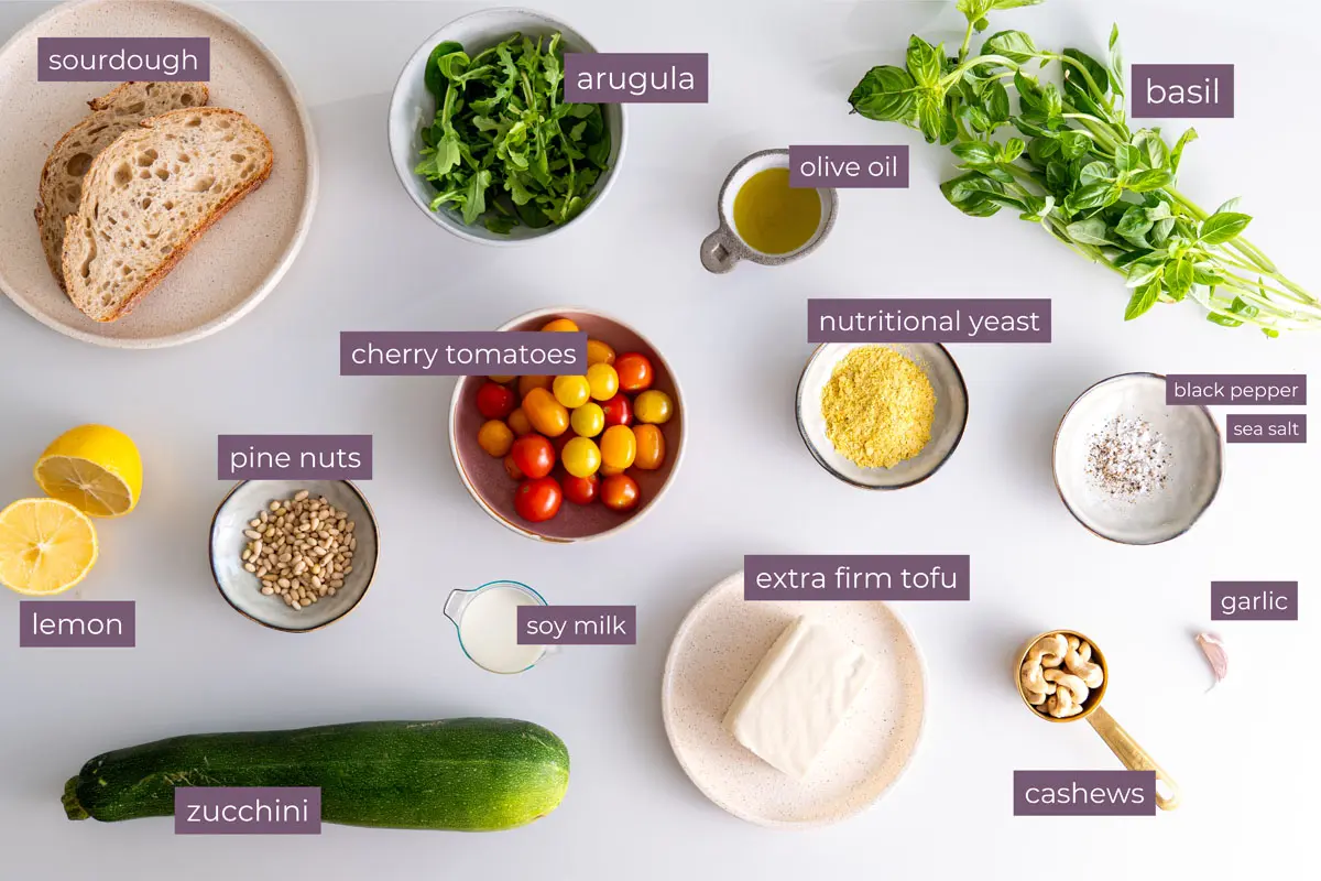 Vibrant ingredients for a high-protein pesto bowl on a white surface.