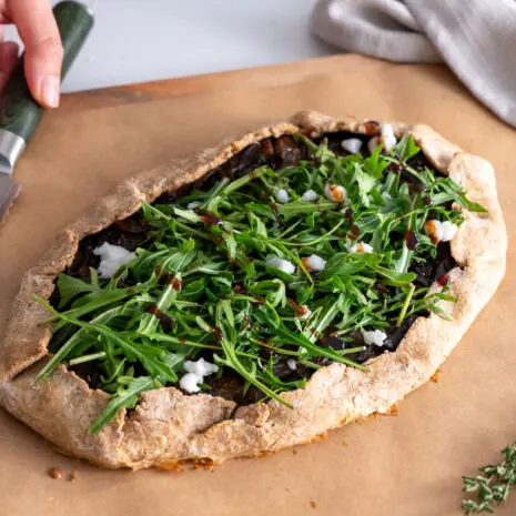 Galette topped with fresh arugula, plant-based feta, and balsamic glaze.