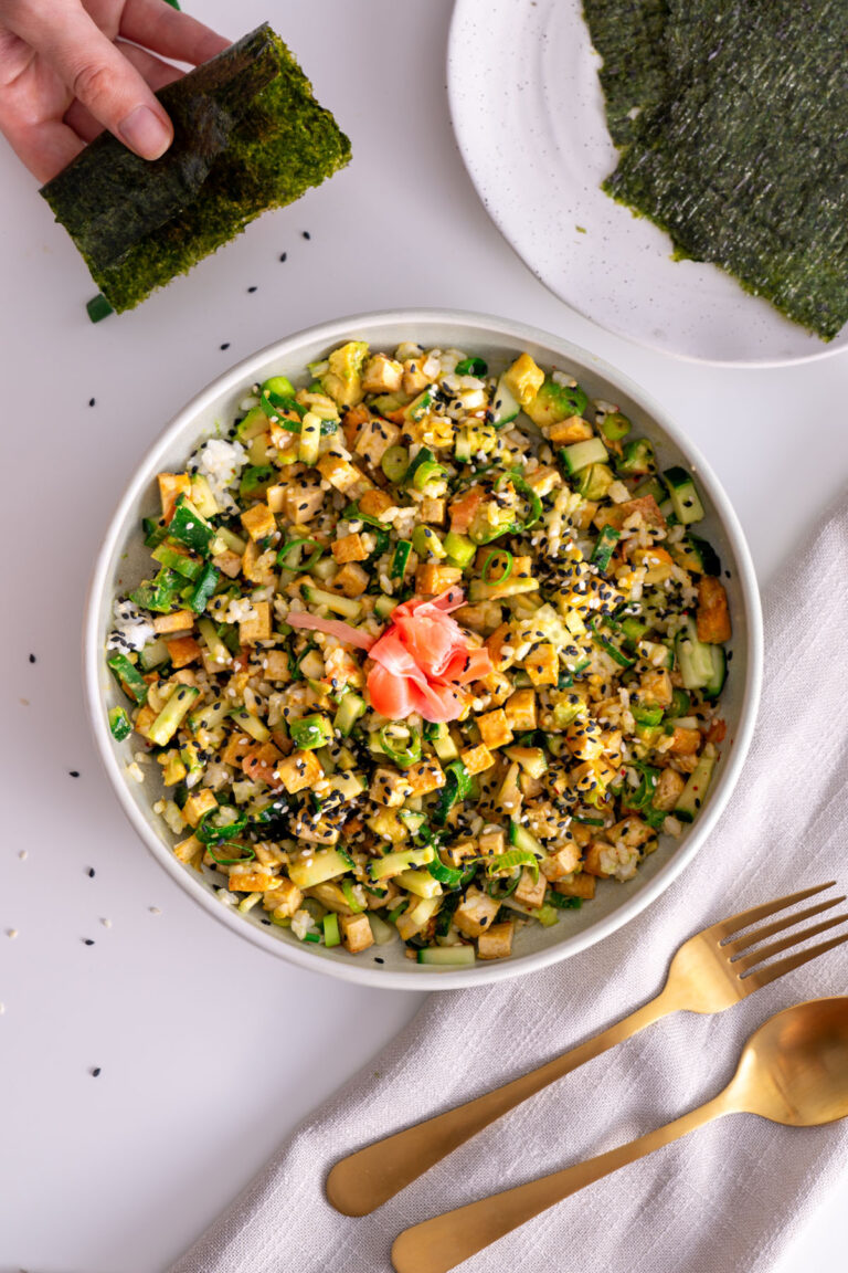 Close-up of High-Protein Vegan Sushi Bowl with nori sheet in hand.