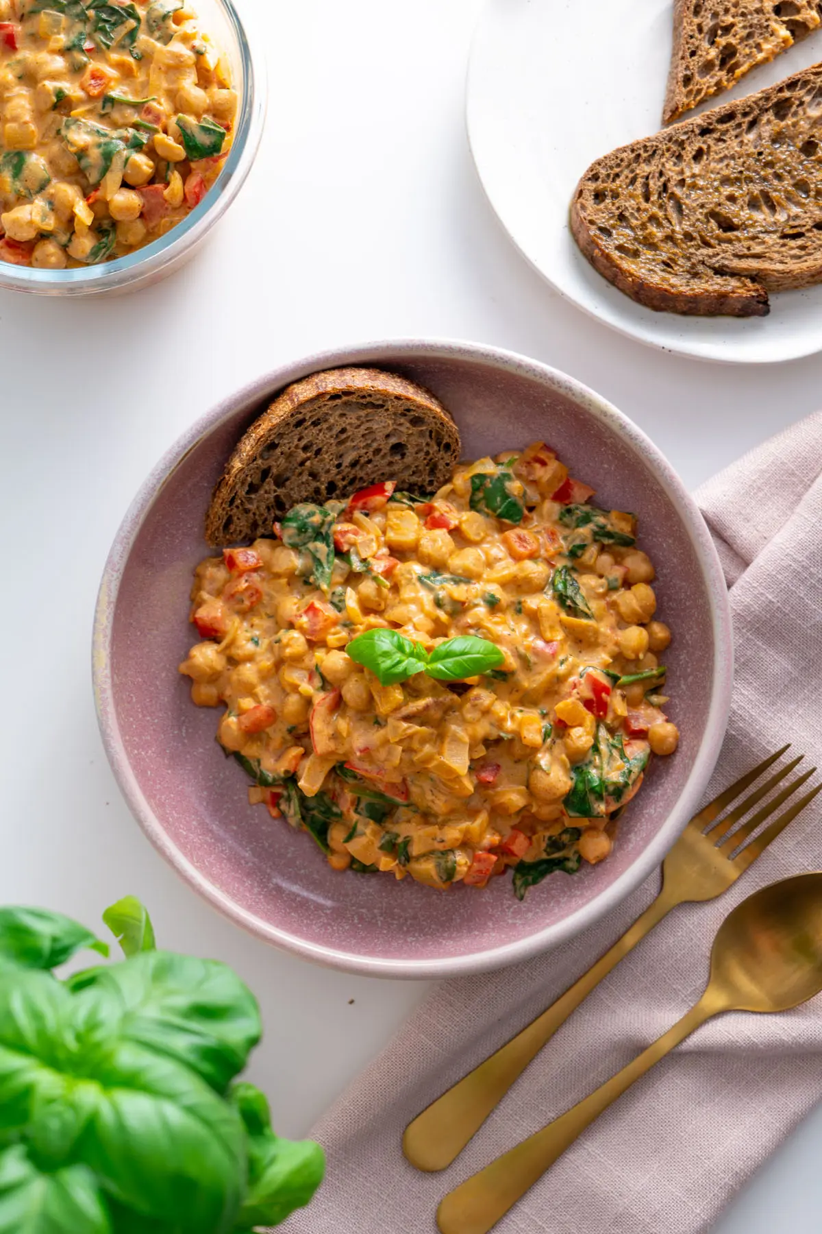 Overhead shot of a bowl of creamy chickpeas and spinach served with bread.