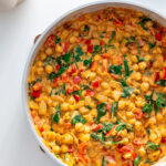 Pan filled with cooked Marry Me Chickpeas with spinach and red bell pepper.
