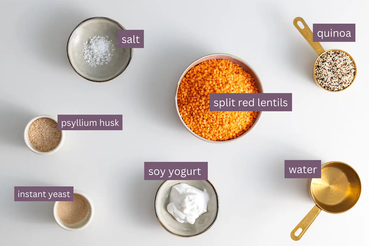 Vibrant ingredients for a red lentil quinoa bread recipe on a white surface.