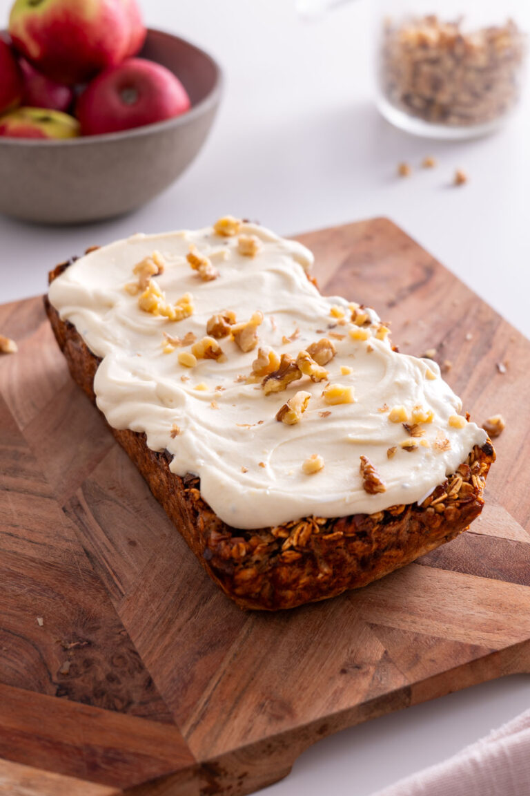 Loaf of apple pie baked oats topped with protein icing and chopped walnuts.