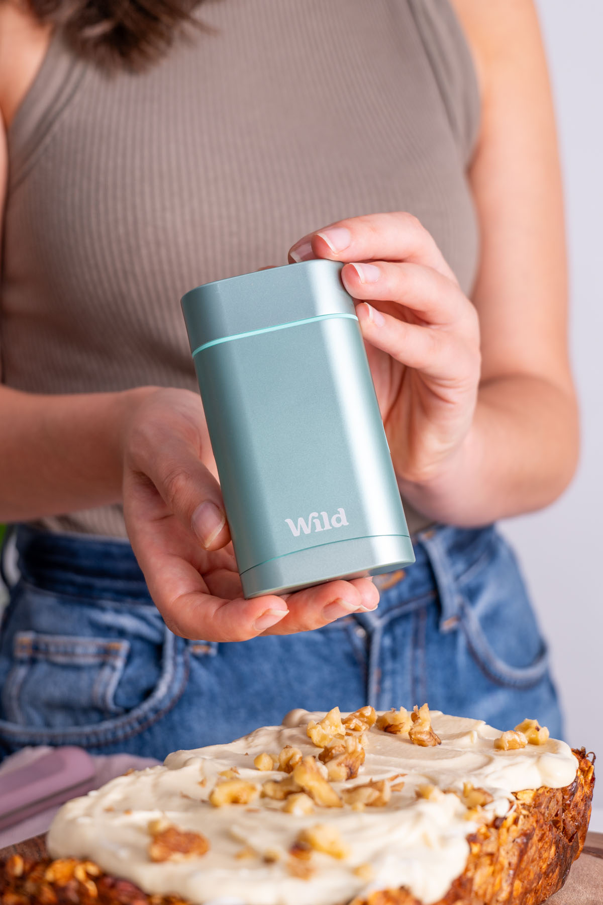 Sarah Cobacho holding a Wild deodorant container near a loaf of apple pie baked oats.