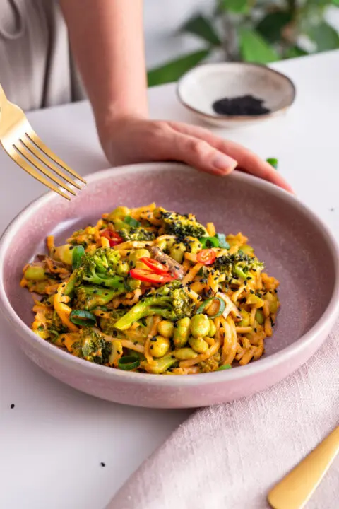 Sarah Cobacho holding a fork over a bowl of peanut gochujang noodles.