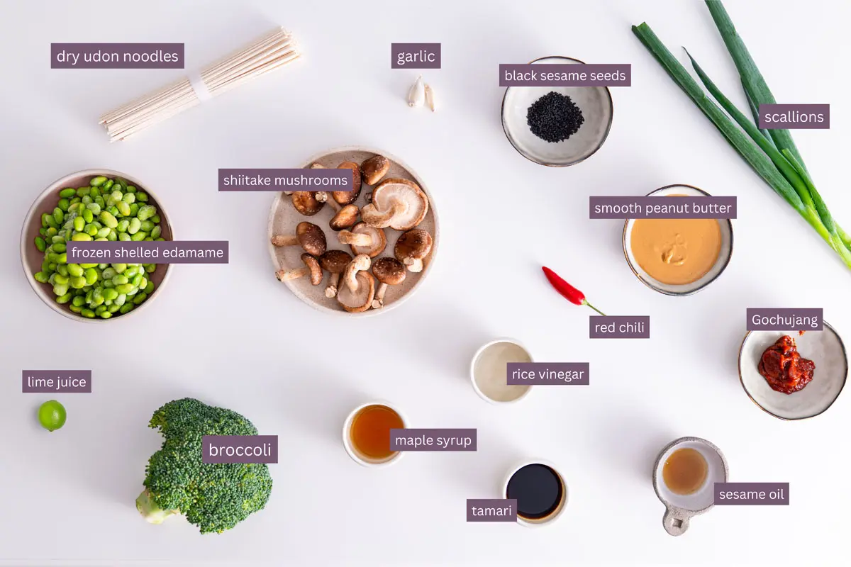 Vibrant ingredients for peanut gochujang noodles on a white surface.