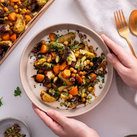 Sarah Cobacho holding a bowl of Sweet & Spicy Roasted Veggies on a White Bean Spread.