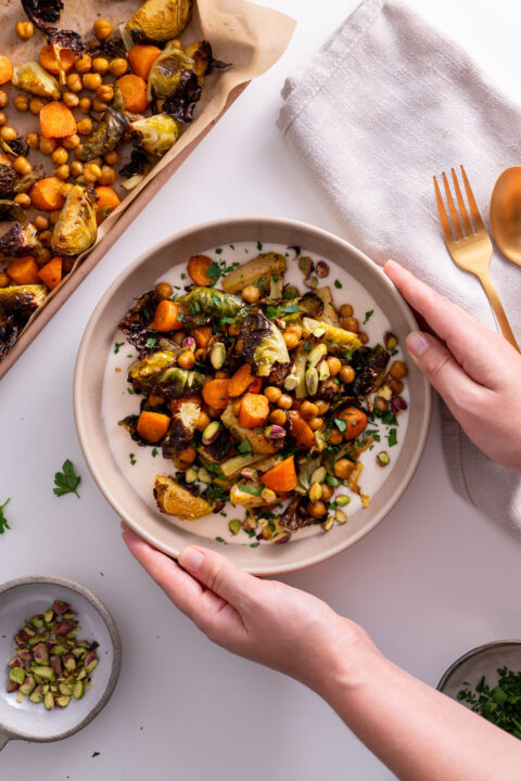 Sarah Cobacho holding a bowl of Sweet & Spicy Roasted Veggies on a White Bean Spread.
