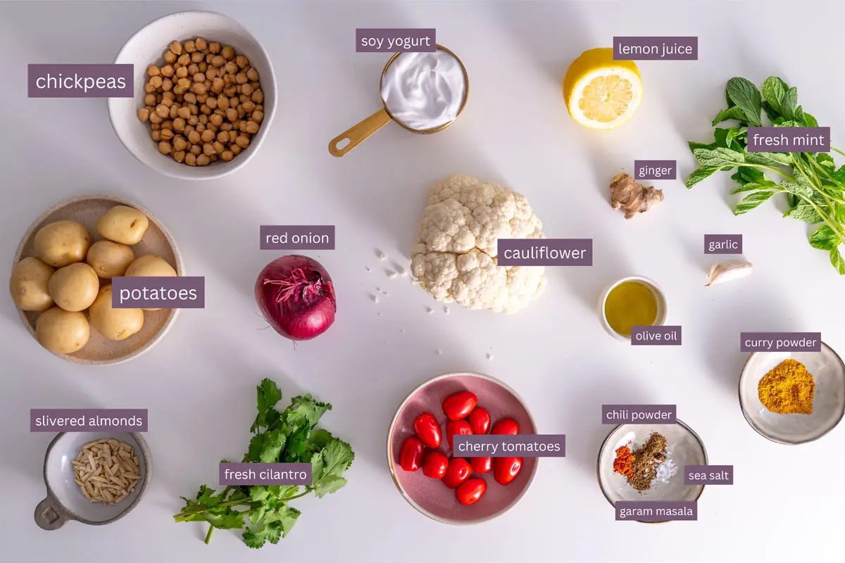 Soy yogurt on a white surface with other ingredients for curry baked veggies recipe.