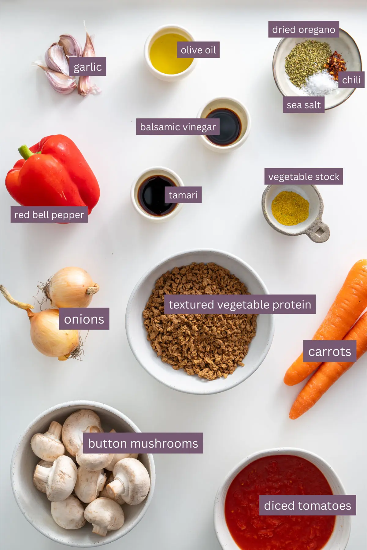 Vibrant ingredients for high-protein vegan lasagna on a white surface, featuring carrots, button mushrooms, and textured vegetable protein.