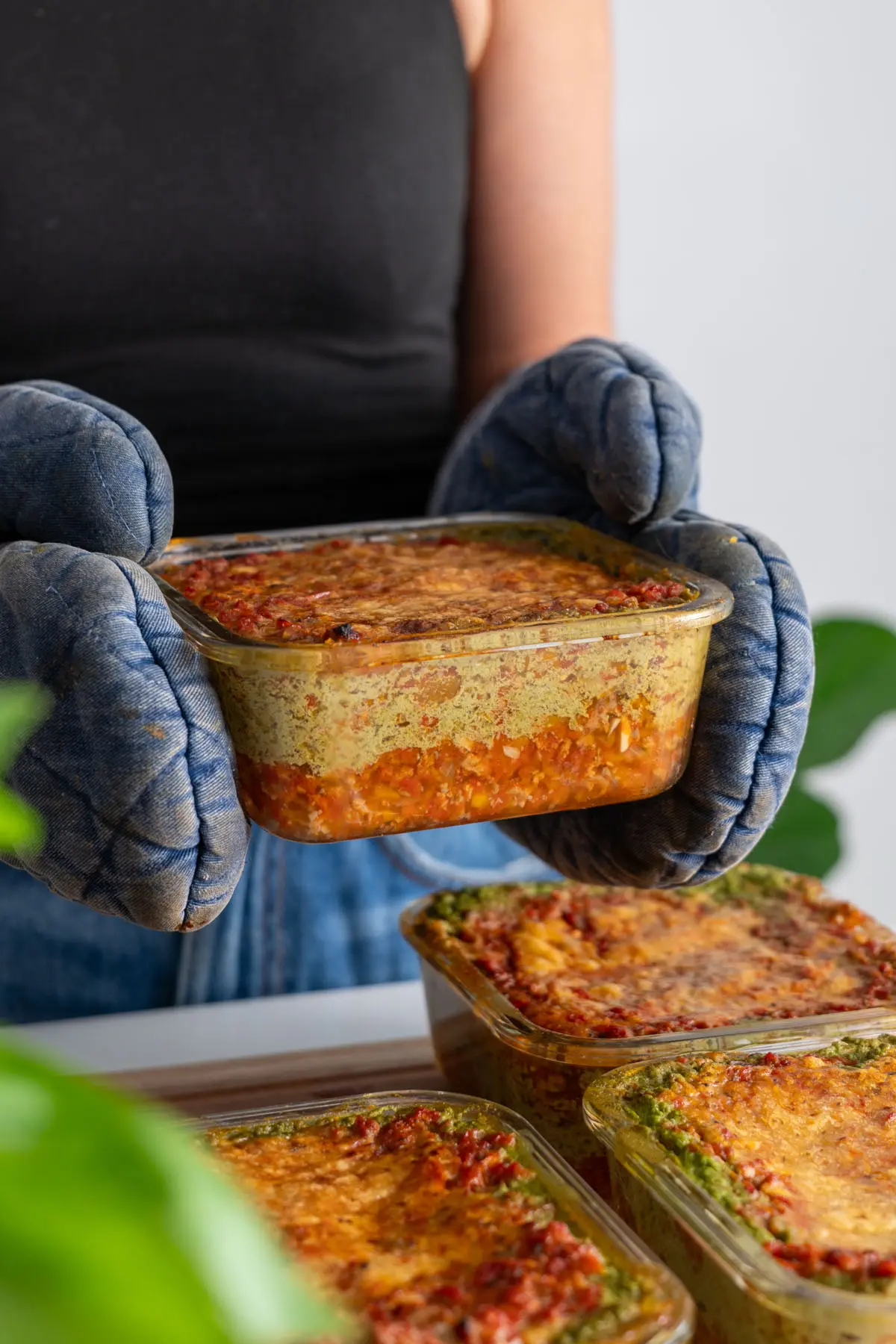 Close-up of a meal prep container filled with high-protein vegan lasagna showing the layers of vegetables and creamy sauce.