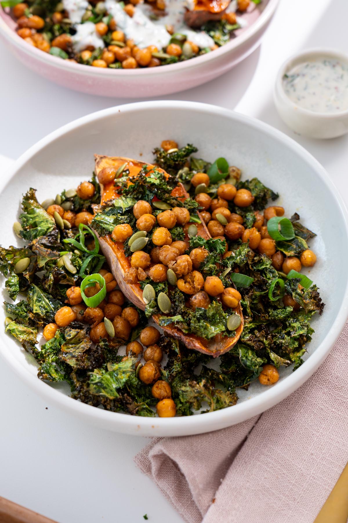 Roasted sweet potato bowl with crispy kale, chickpeas, pumpkin seeds and yogurt sauce.
