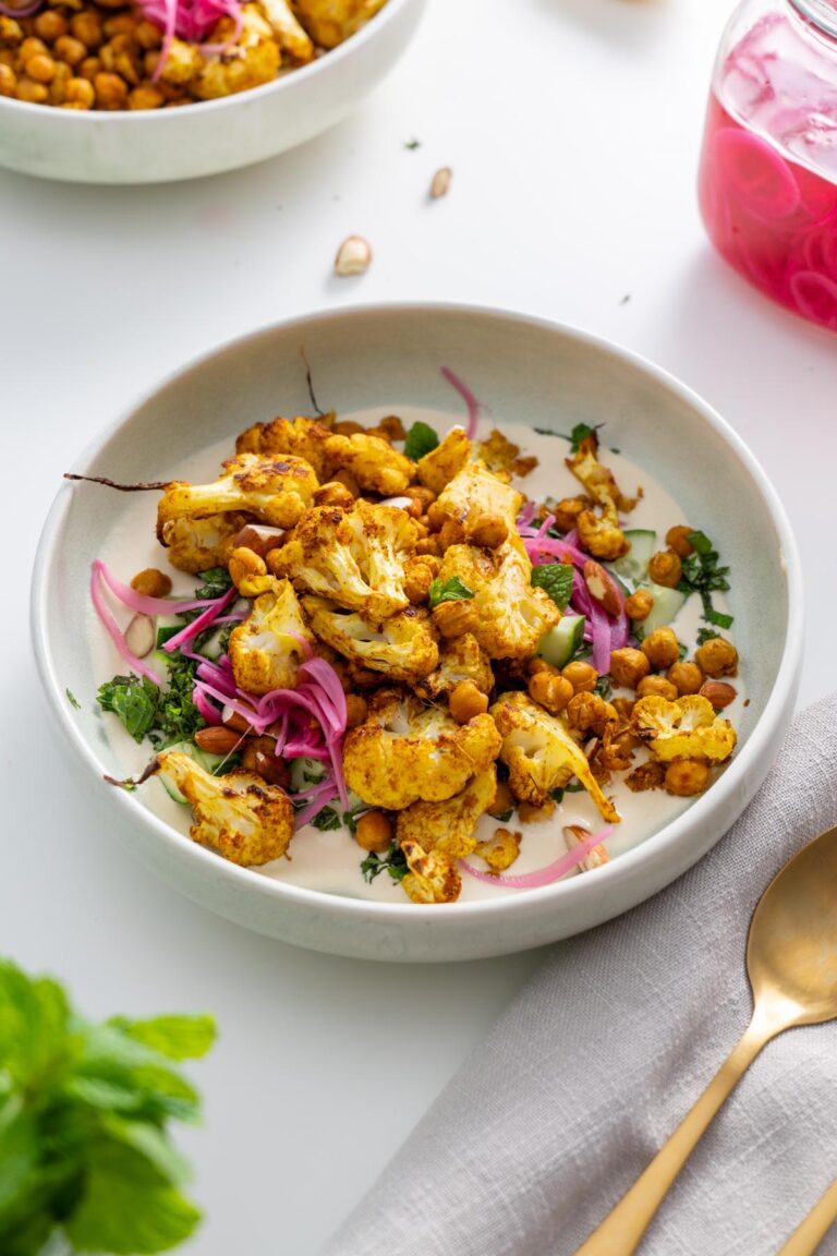 A beautifully plated tandoori spiced cauliflower bowl with chickpeas, pickled onions, and fresh herbs.