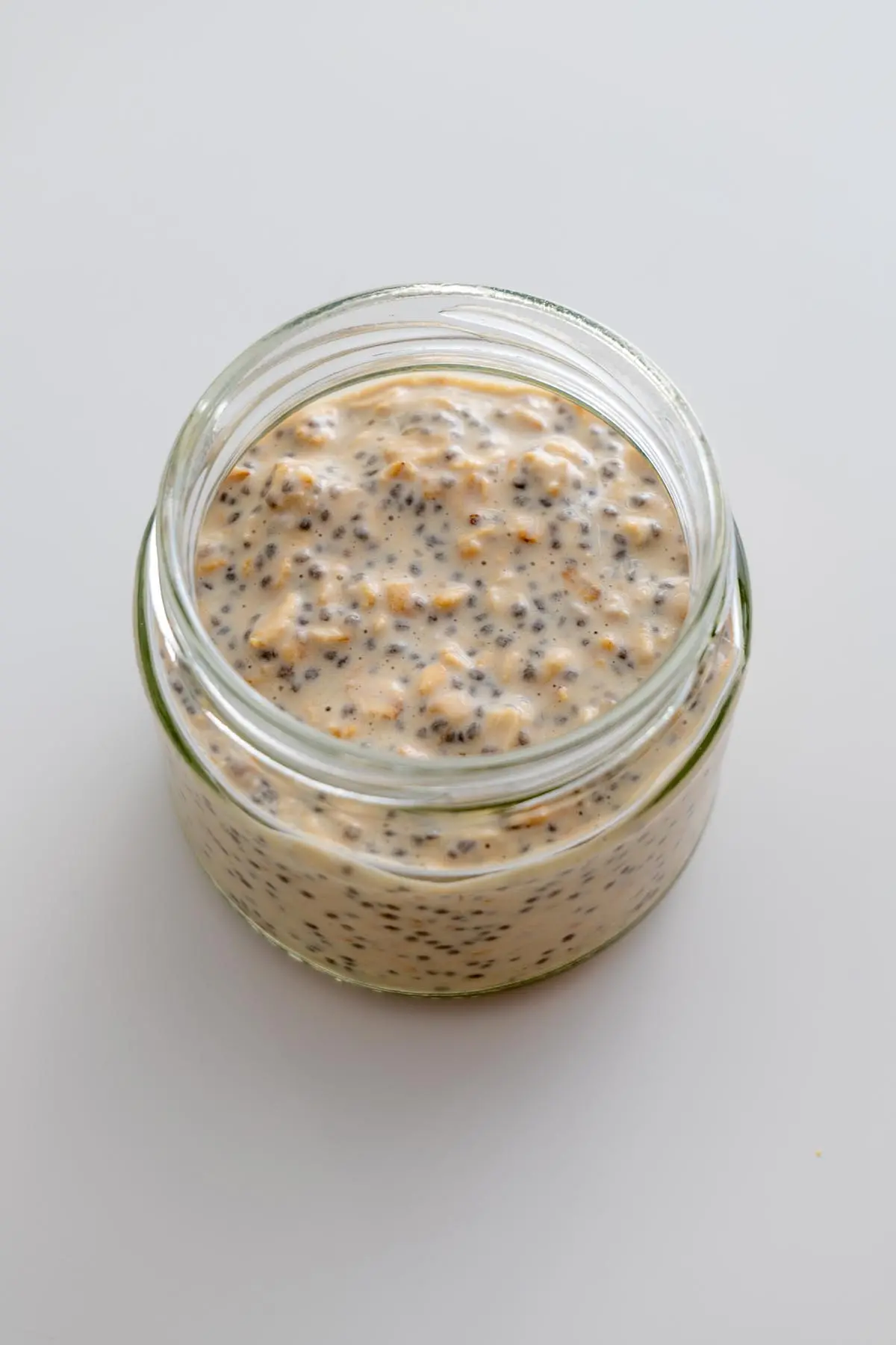 Chilled Snickers overnight oats with visible oats and chia seeds in a glass jar.