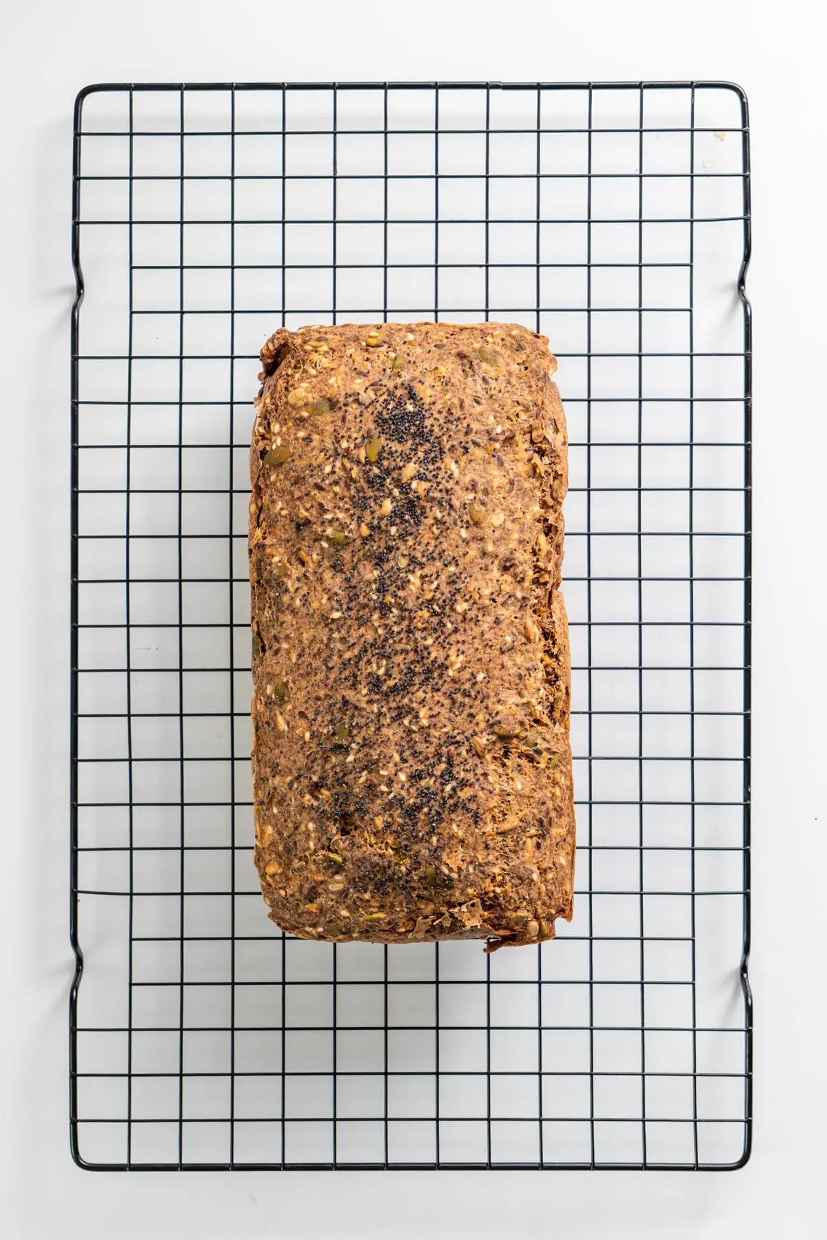 Overhead view of gluten-free seeded bread cooling on a wire rack