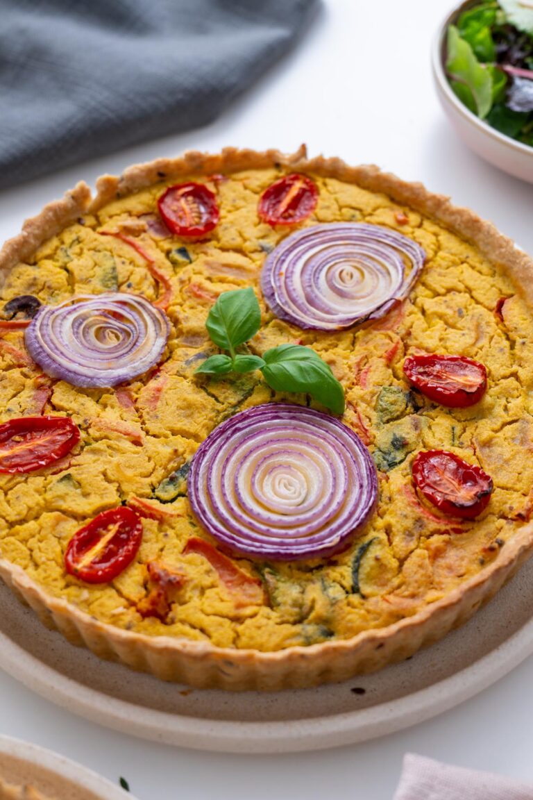 Close-up of golden-baked vegan quiche with colorful topping details