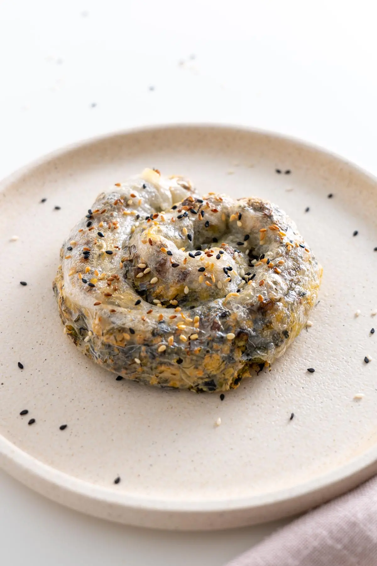 Overhead view of a whole rice paper roll spanakopita on a plate with gold cutlery