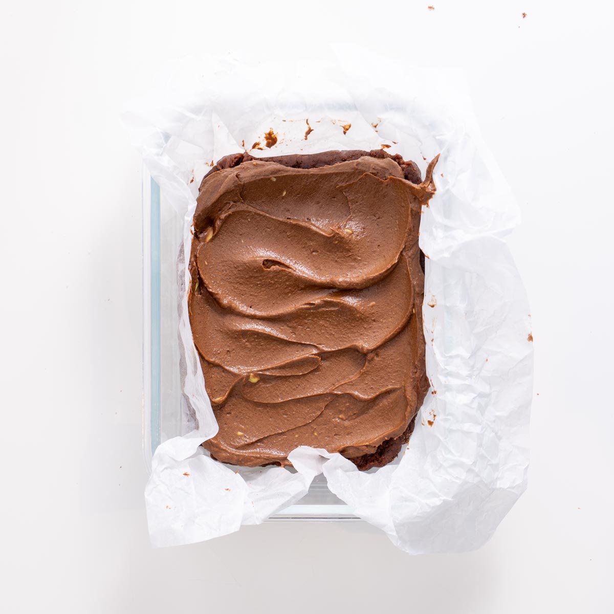 Tray of fudgy no-bake brownies topped with avocado ganache before slicing