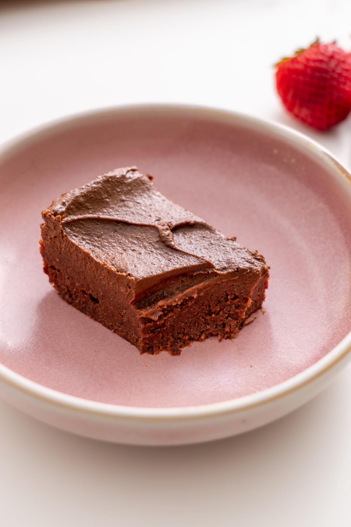 Fudgy no-bake brownie slice with creamy avocado ganache on a pink plate