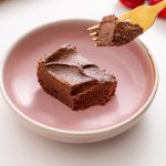 Rich fudgy no-bake brownie slice on a pink plate with a forkful lifted