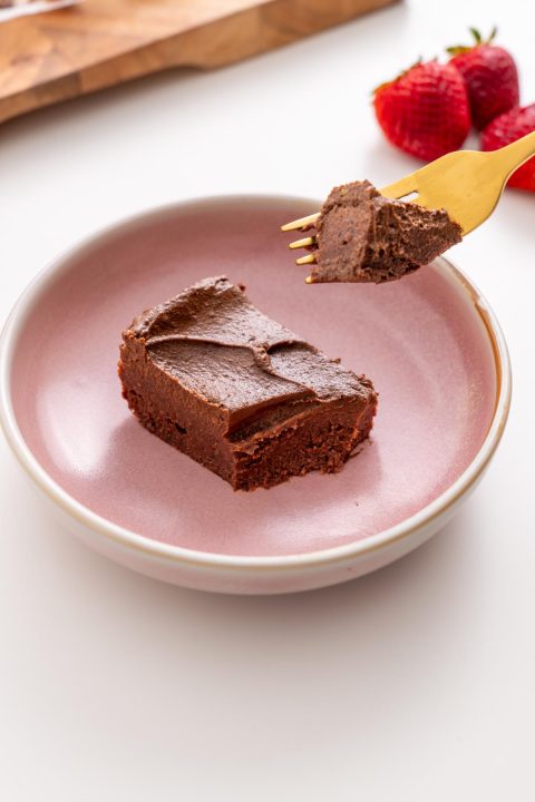 Rich fudgy no-bake brownie slice on a pink plate with a forkful lifted
