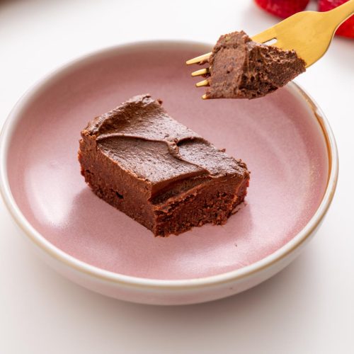 Rich fudgy no-bake brownie slice on a pink plate with a forkful lifted