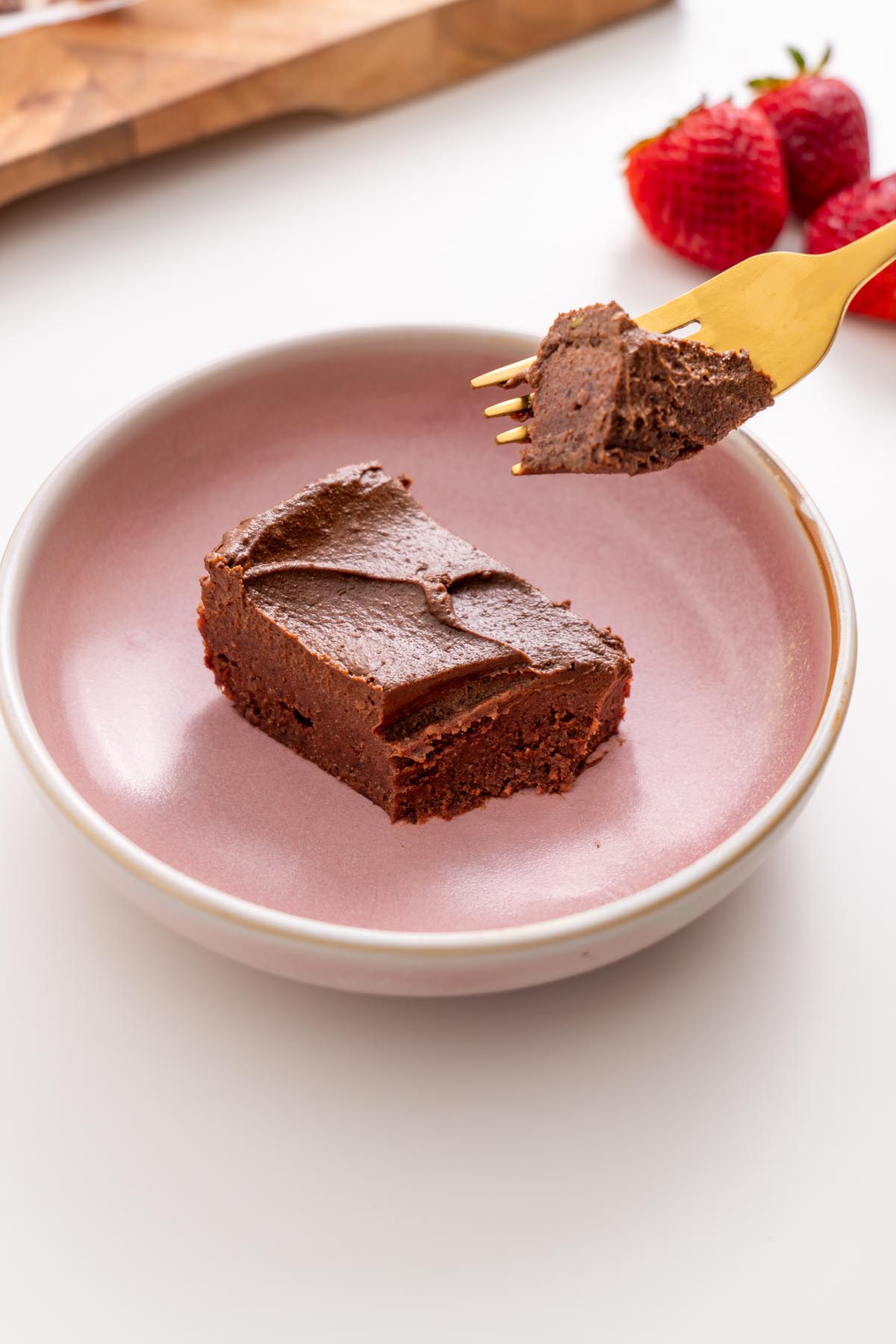 Rich fudgy no-bake brownie slice on a pink plate with a forkful lifted