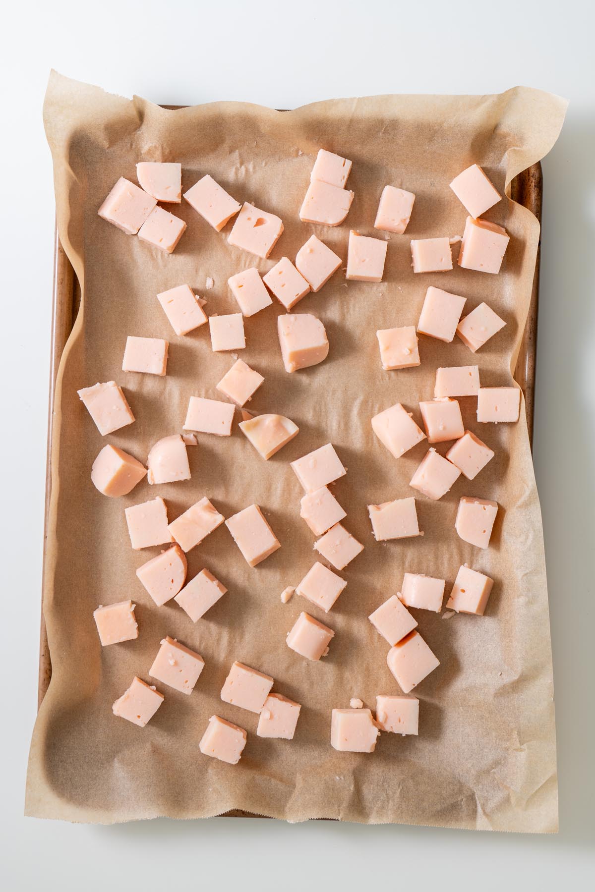 Parchment-lined tray with red lentil tofu cubes spaced evenly before cooking