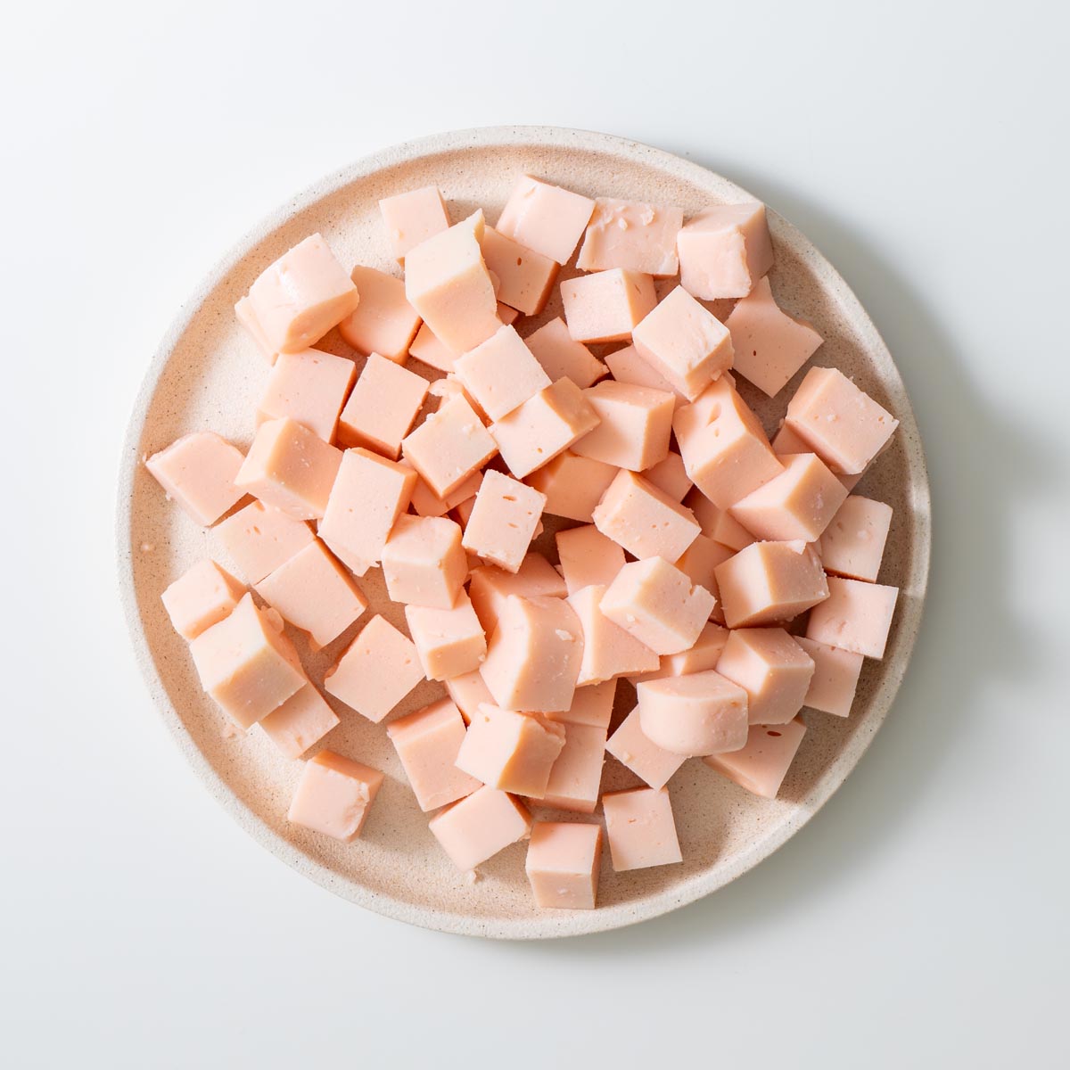 Plate of freshly set red lentil tofu cubes on a white background