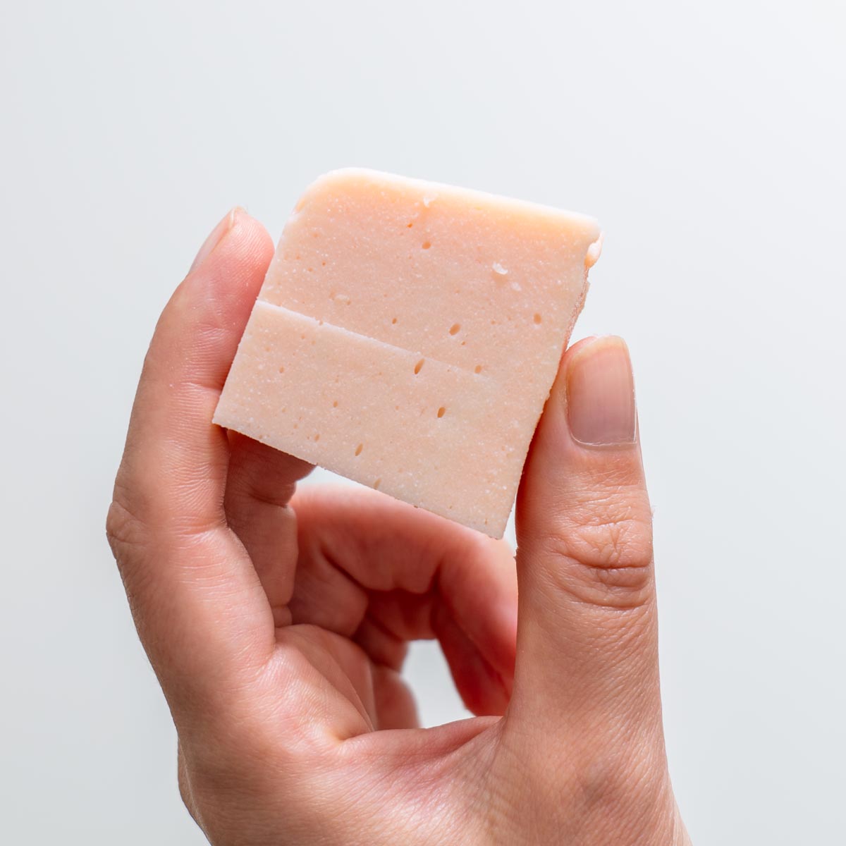 Sarah Cobacho holding a large block of red lentil tofu showing smooth texture