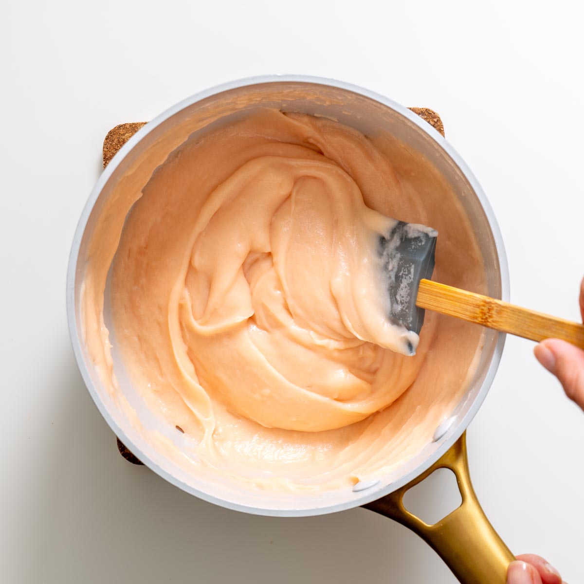 Pot of thick cooked red lentil mixture being stirred with a spatula