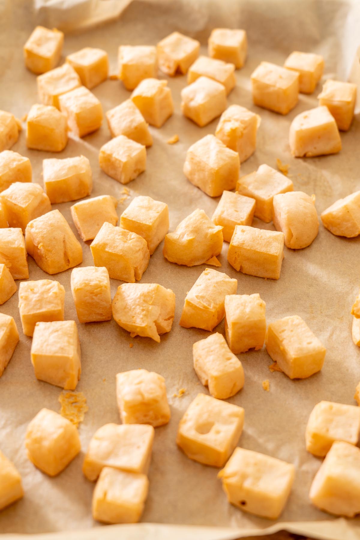 Cubes of baked red lentil tofu arranged on parchment paper