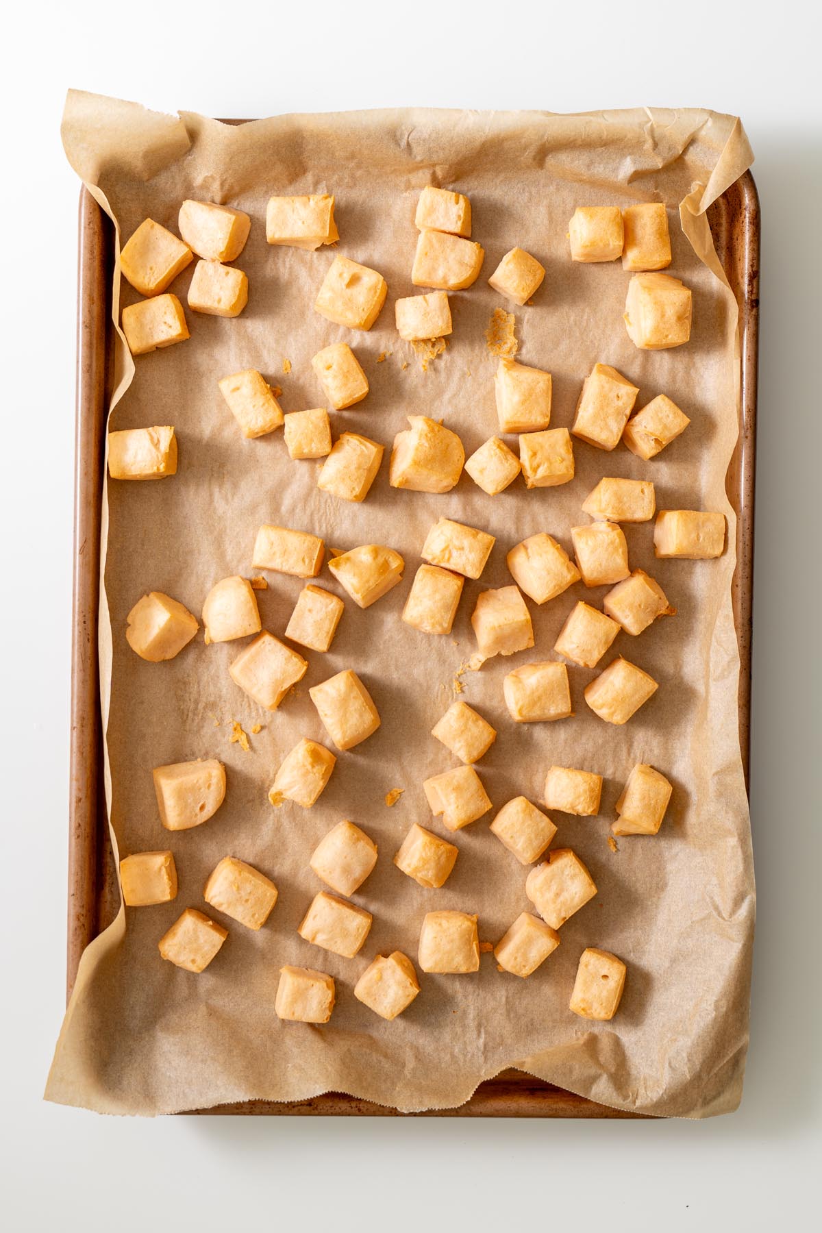 Tray of baked red lentil tofu cubes on parchment-lined baking sheet