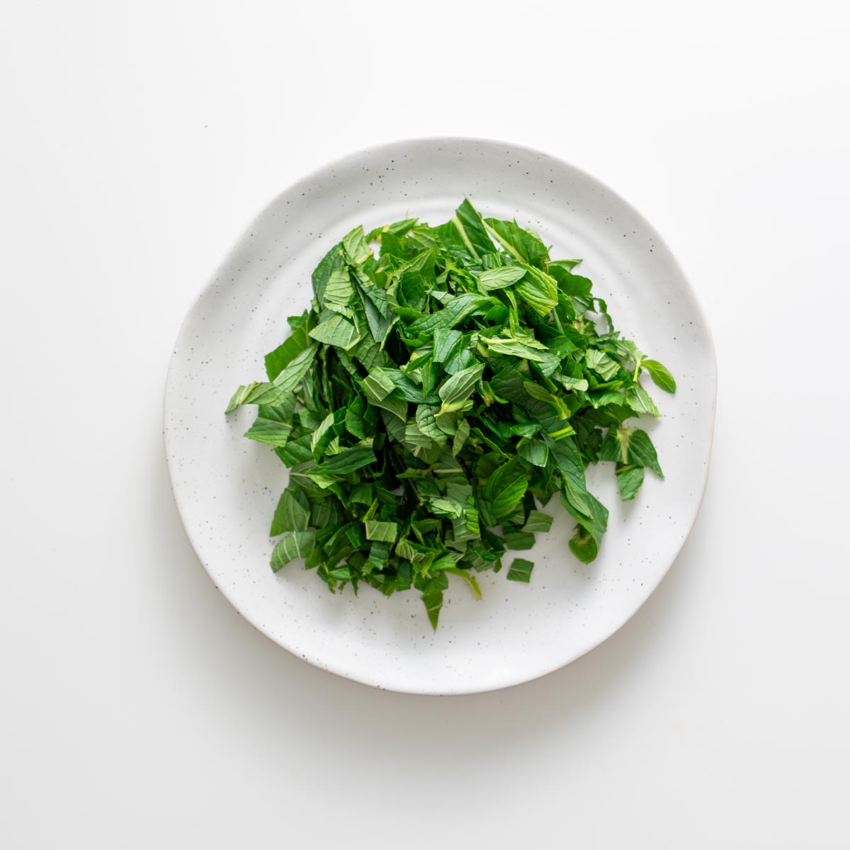 Chopped fresh mint on a plate for peanut vermicelli salad jars