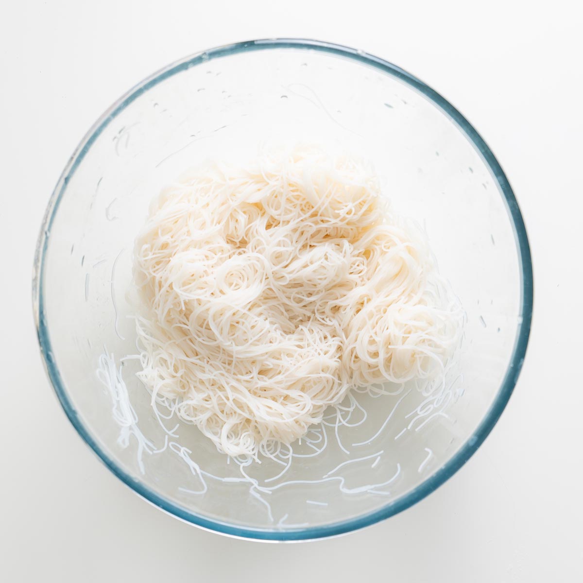 Cooked and cooled rice vermicelli noodles in a clear glass bowl