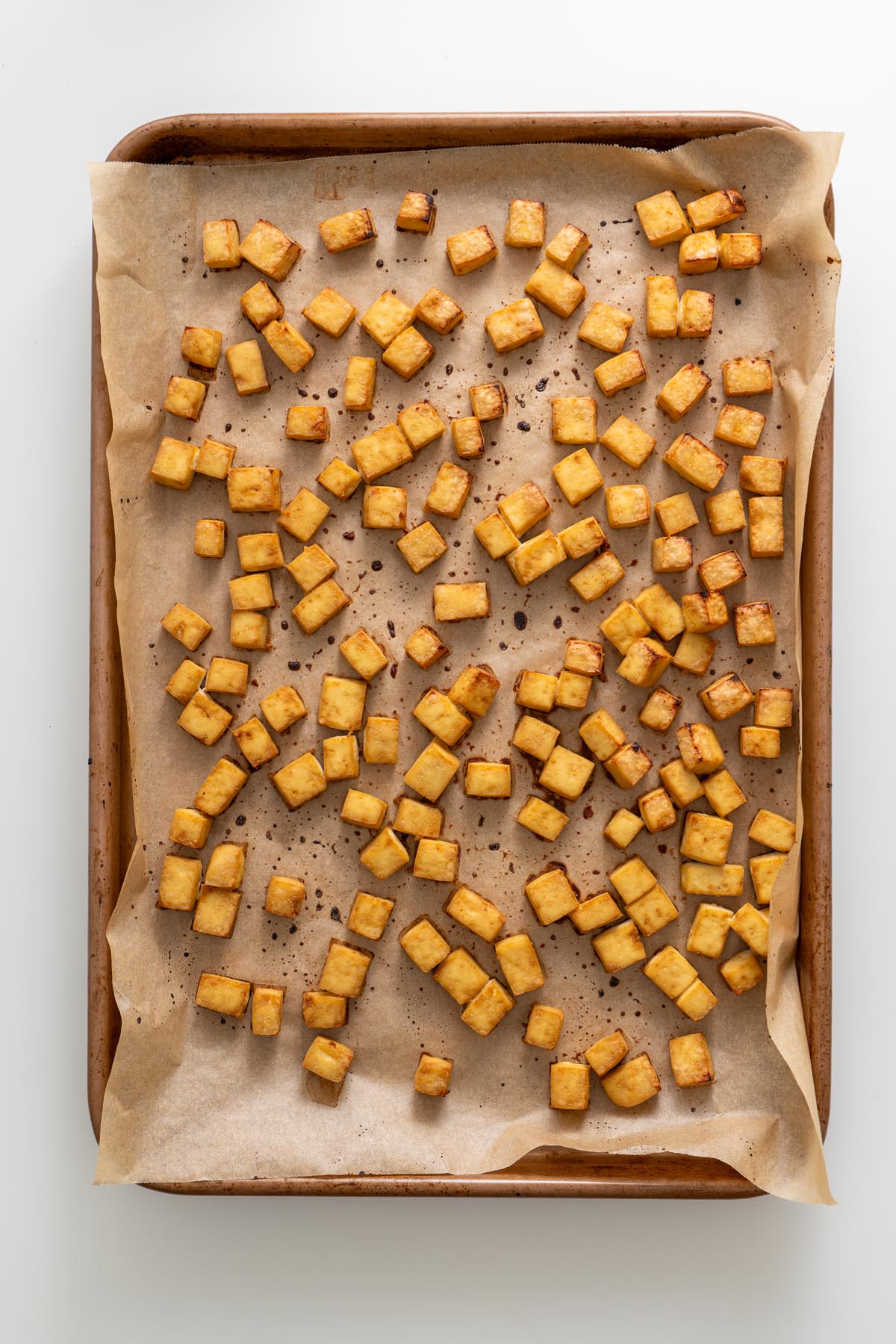 Golden baked tofu cubes on a parchment-lined tray fresh from the oven