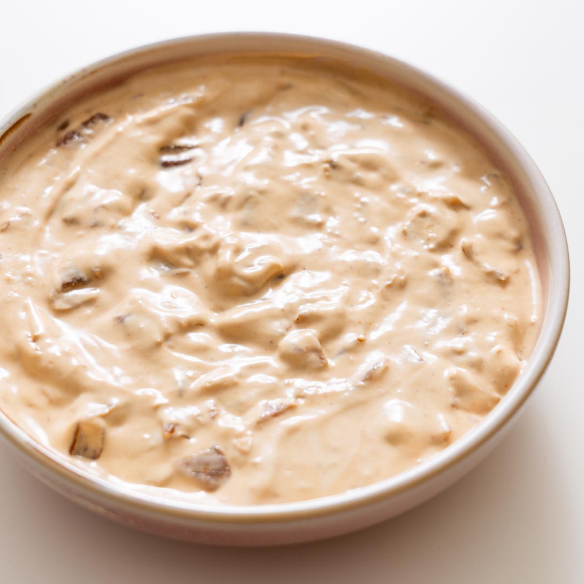 Close-up of creamy French onion dip showing caramelized onion pieces.