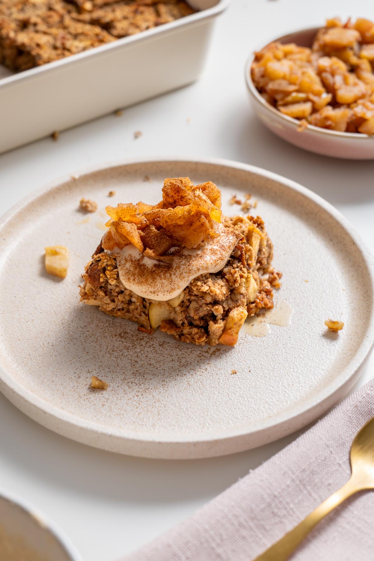 Slice of apple pie baked oats topped with stewed apples on a plate.